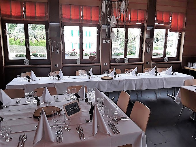 Petite salle lumineuse dressée pour un repas de famille au Restaurant Maison de Ville Vuippens